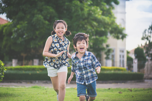 cute asian children runing together in the park outdoors